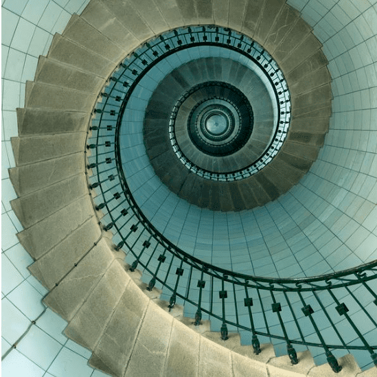 A spiraling staircase viewed from below, creating a mesmerizing geometric pattern.